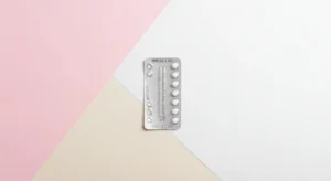 Minimalist medical flat lay, blister pack of modern oral contraceptive pills on a clean pastel background